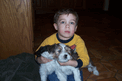 Small boy in a yellow shirt holding a tan-and-white Tibetan Terrier