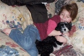 Young girl lying on pillows with black-and-white Tibetan Terrier