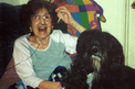 Three Tibetan Terrier puppies (one black and white, and two sable) sitting with toys in a brown chair